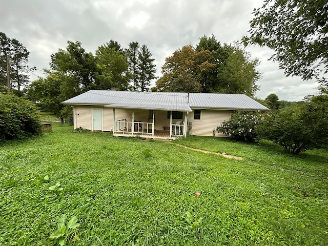 back of house with metal roof and a lawn