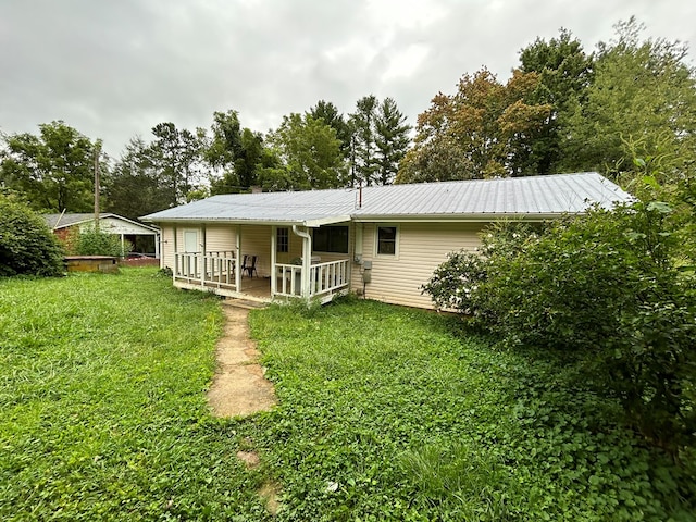 back of house featuring metal roof and a yard