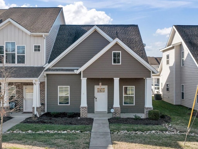 view of front of property featuring brick siding, a porch, a shingled roof, central AC unit, and board and batten siding