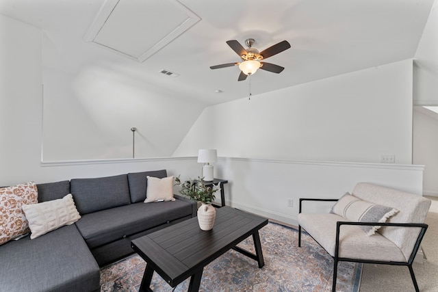 living area featuring ceiling fan, lofted ceiling, visible vents, baseboards, and attic access