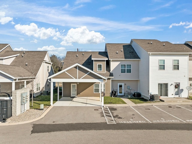 view of front of house featuring uncovered parking, cooling unit, roof with shingles, and a residential view