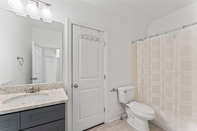 bathroom with toilet, vanity, and baseboards