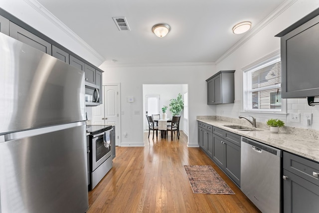 kitchen featuring crown molding, stainless steel appliances, gray cabinets, visible vents, and a sink