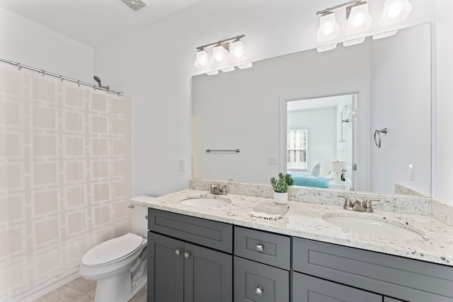 ensuite bathroom with toilet, double vanity, a sink, and ensuite bathroom