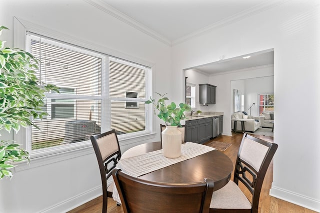 dining space with dark wood-type flooring, crown molding, and baseboards