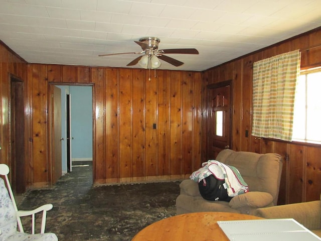 living room with ceiling fan and wood walls