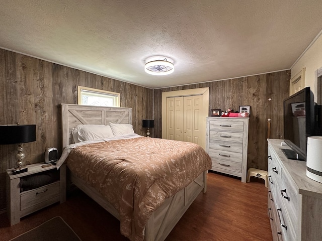 bedroom featuring dark wood finished floors, wooden walls, a closet, and a textured ceiling