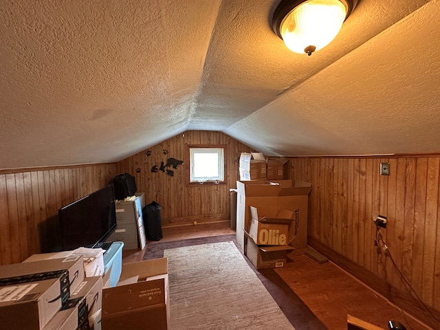 bonus room with vaulted ceiling, wood finished floors, wood walls, and a textured ceiling