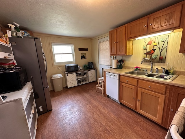 kitchen with dark wood-type flooring, dishwasher, light countertops, brown cabinets, and a sink