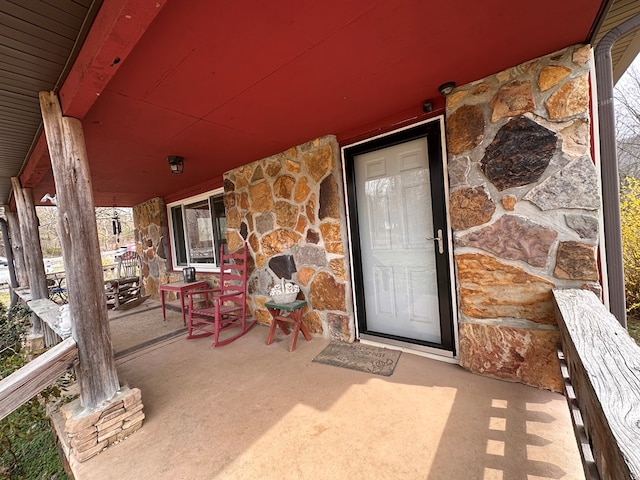 entrance to property featuring stone siding and covered porch