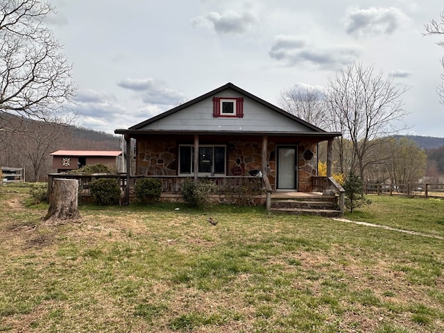 view of front facade with stone siding, covered porch, and a front yard