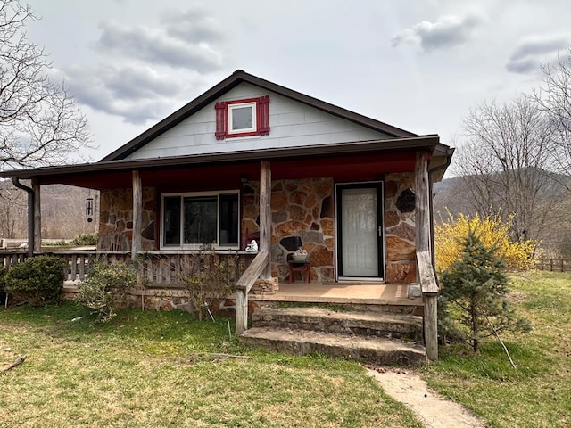 view of front facade featuring stone siding, covered porch, and a front yard