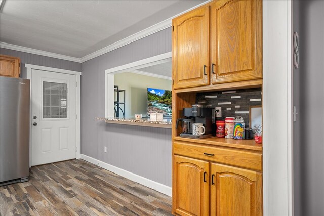 kitchen with light countertops, decorative backsplash, ornamental molding, freestanding refrigerator, and dark wood-type flooring