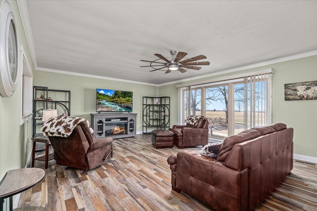 living room with ornamental molding, wood finished floors, and a glass covered fireplace