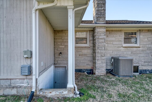 view of exterior entry with central AC and stone siding