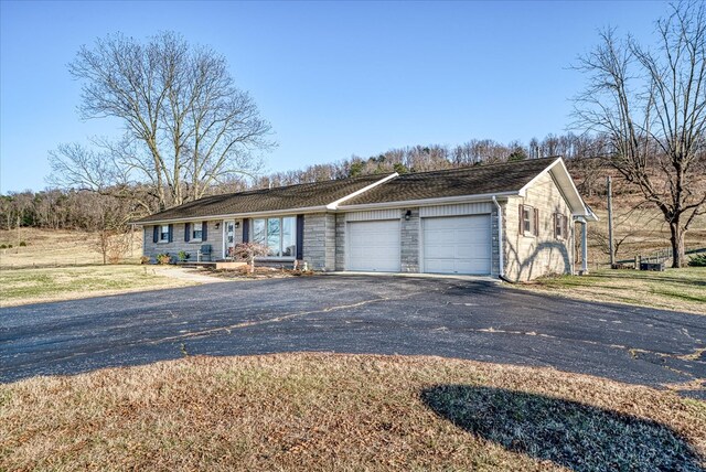 view of front of home with a garage, stone siding, and aphalt driveway