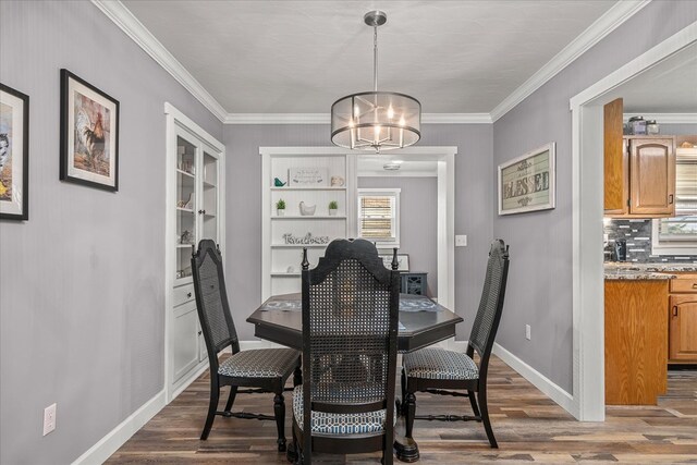 dining area featuring ornamental molding, an inviting chandelier, wood finished floors, and baseboards