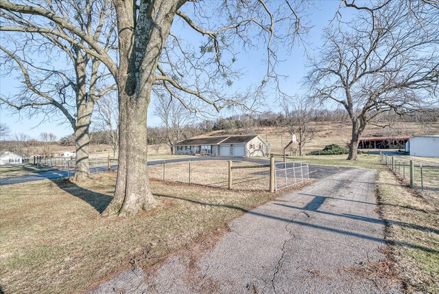 view of yard featuring a garage, a rural view, an outdoor structure, and fence