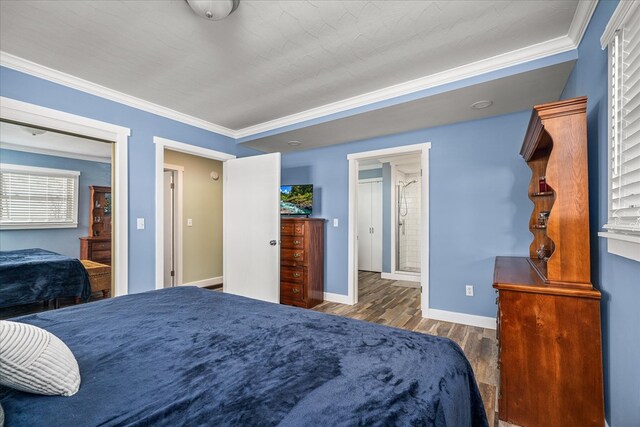 bedroom featuring ornamental molding, connected bathroom, dark wood finished floors, and baseboards