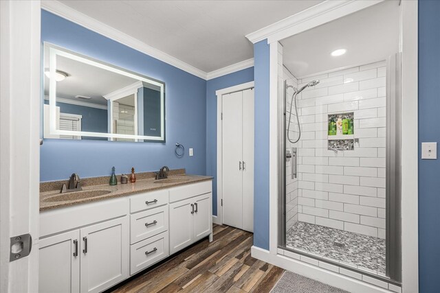 bathroom featuring ornamental molding, a stall shower, a sink, and wood finished floors