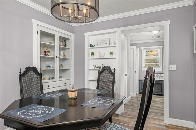 dining area with a notable chandelier, baseboards, crown molding, and wood finished floors