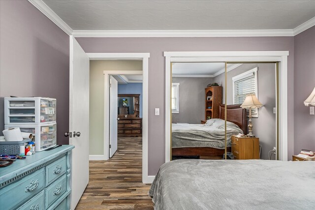 bedroom with dark wood-type flooring, a closet, ornamental molding, and baseboards