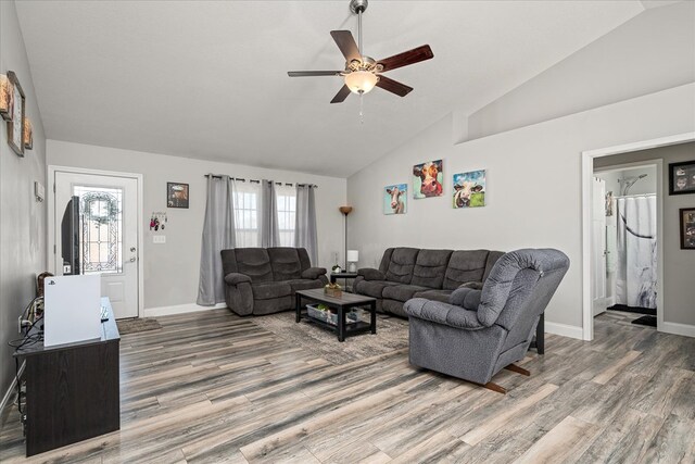 living area with baseboards, a ceiling fan, vaulted ceiling, and dark wood-style flooring