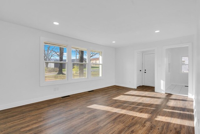 unfurnished room with baseboards, dark wood finished floors, visible vents, and recessed lighting