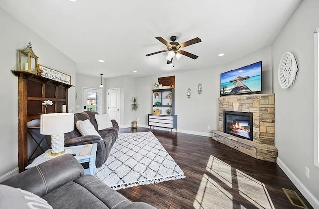 living room featuring dark wood-type flooring, visible vents, a fireplace, and baseboards