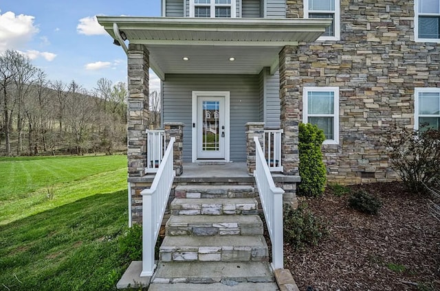 view of exterior entry with stone siding and a lawn