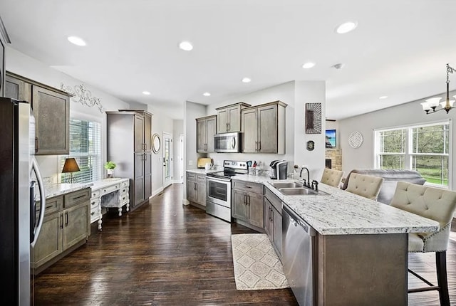 kitchen featuring dark wood-style floors, a breakfast bar, open floor plan, stainless steel appliances, and a sink