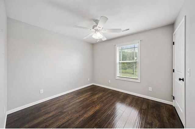 spare room featuring baseboards, visible vents, ceiling fan, and dark wood-style flooring