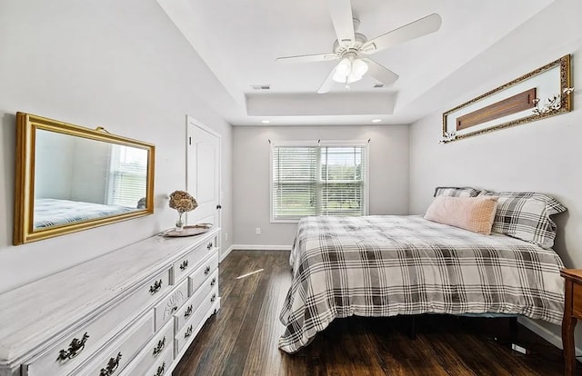 bedroom featuring recessed lighting, dark wood-type flooring, a ceiling fan, baseboards, and a tray ceiling