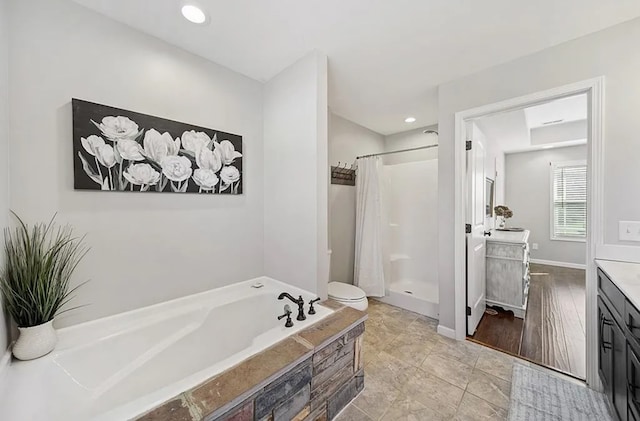 bathroom featuring a garden tub, a shower stall, baseboards, and vanity