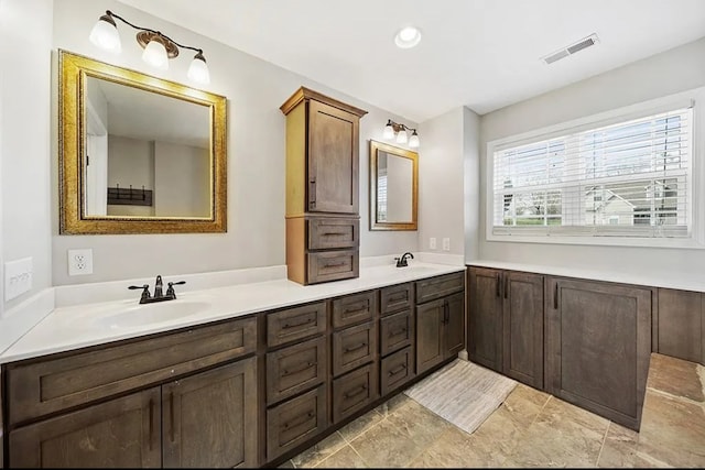 full bath featuring double vanity, a sink, and visible vents