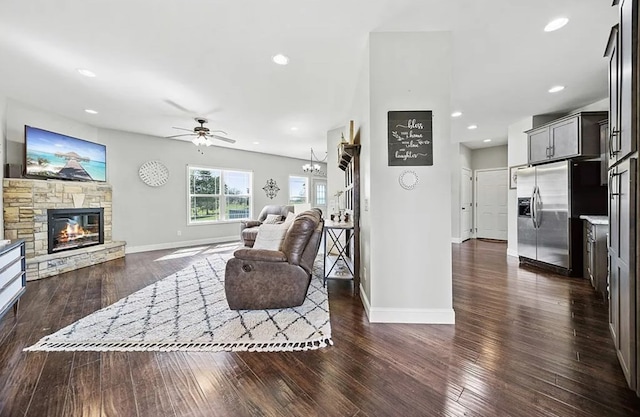 living room featuring a stone fireplace, dark wood-style flooring, and recessed lighting