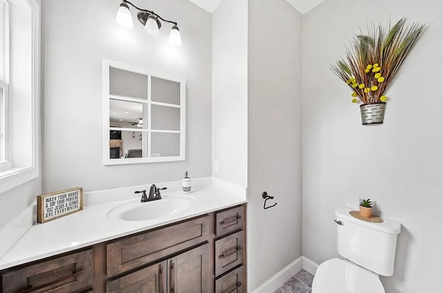 half bathroom featuring baseboards, vanity, and toilet