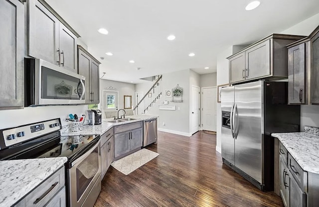 kitchen featuring dark wood-style floors, light stone counters, stainless steel appliances, a sink, and recessed lighting