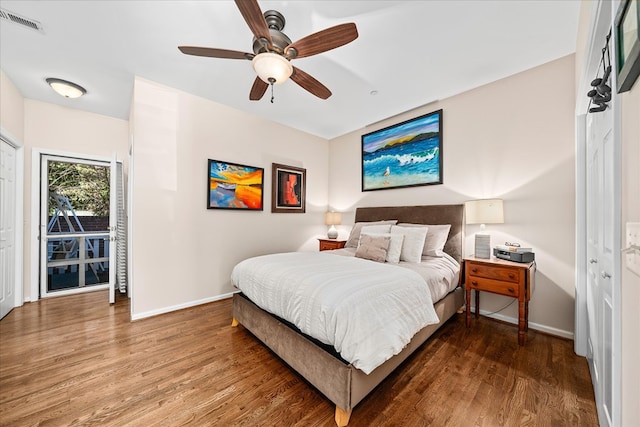 bedroom featuring a ceiling fan, visible vents, baseboards, and wood finished floors