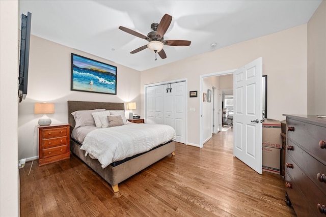 bedroom with ceiling fan, a closet, wood finished floors, and baseboards