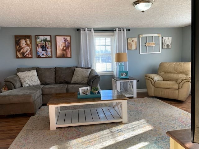 living room with a textured ceiling, baseboards, and wood finished floors