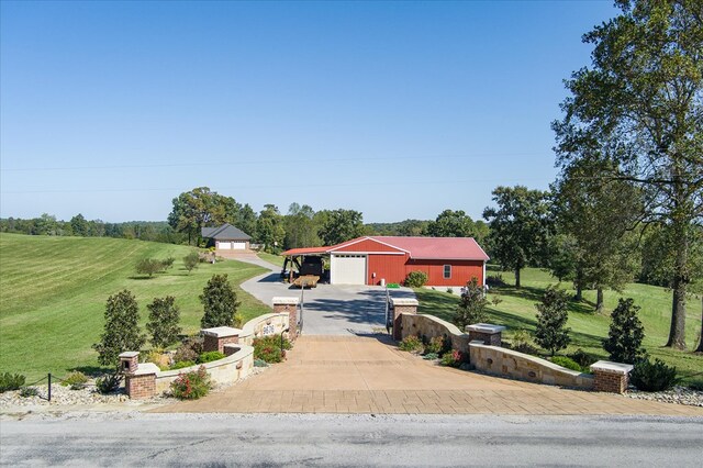 view of front of house featuring an attached garage, driveway, a pole building, and an outdoor structure