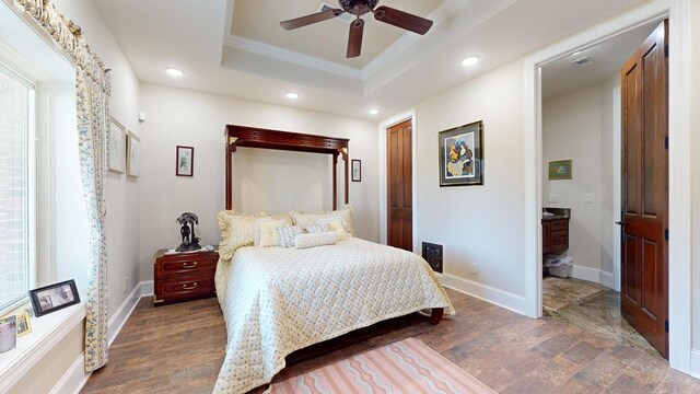 bedroom featuring recessed lighting, dark wood-type flooring, baseboards, ornamental molding, and a tray ceiling