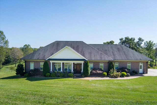 view of front facade featuring a shingled roof, brick siding, and a front lawn