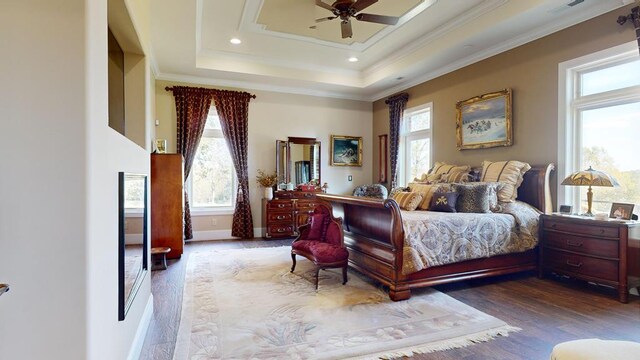 bedroom featuring a tray ceiling, recessed lighting, ornamental molding, wood finished floors, and baseboards