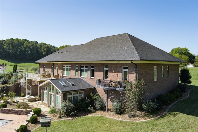 rear view of property featuring a garage, brick siding, a lawn, and stairway