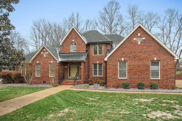 traditional home featuring a shingled roof, a front yard, crawl space, and brick siding