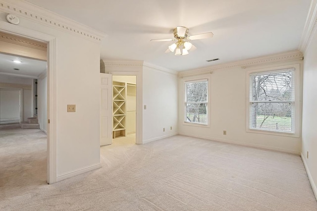 spare room with baseboards, visible vents, crown molding, and light colored carpet