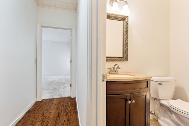 half bath featuring toilet, baseboards, wood finished floors, and vanity