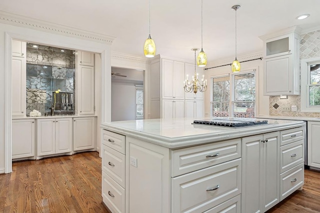 kitchen with black electric cooktop, white cabinets, light countertops, a center island, and decorative light fixtures